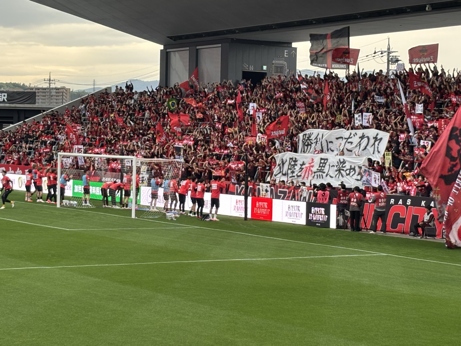 ホームゴール裏の応援風景「勝利にこだわれ」「北陸を赤黒に染めろ」横断幕