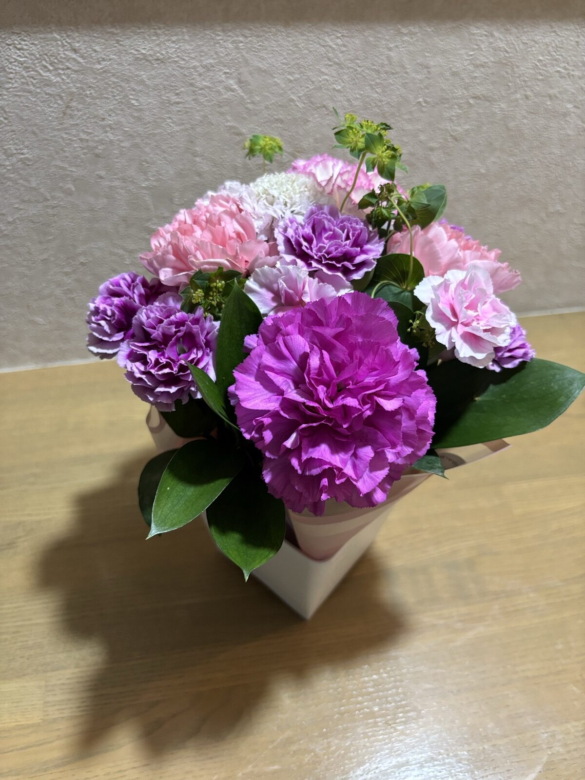 持ち帰ったフローラルアレンジメントを玄関に飾った様子(カーネーション中心のピンク・パープル系)