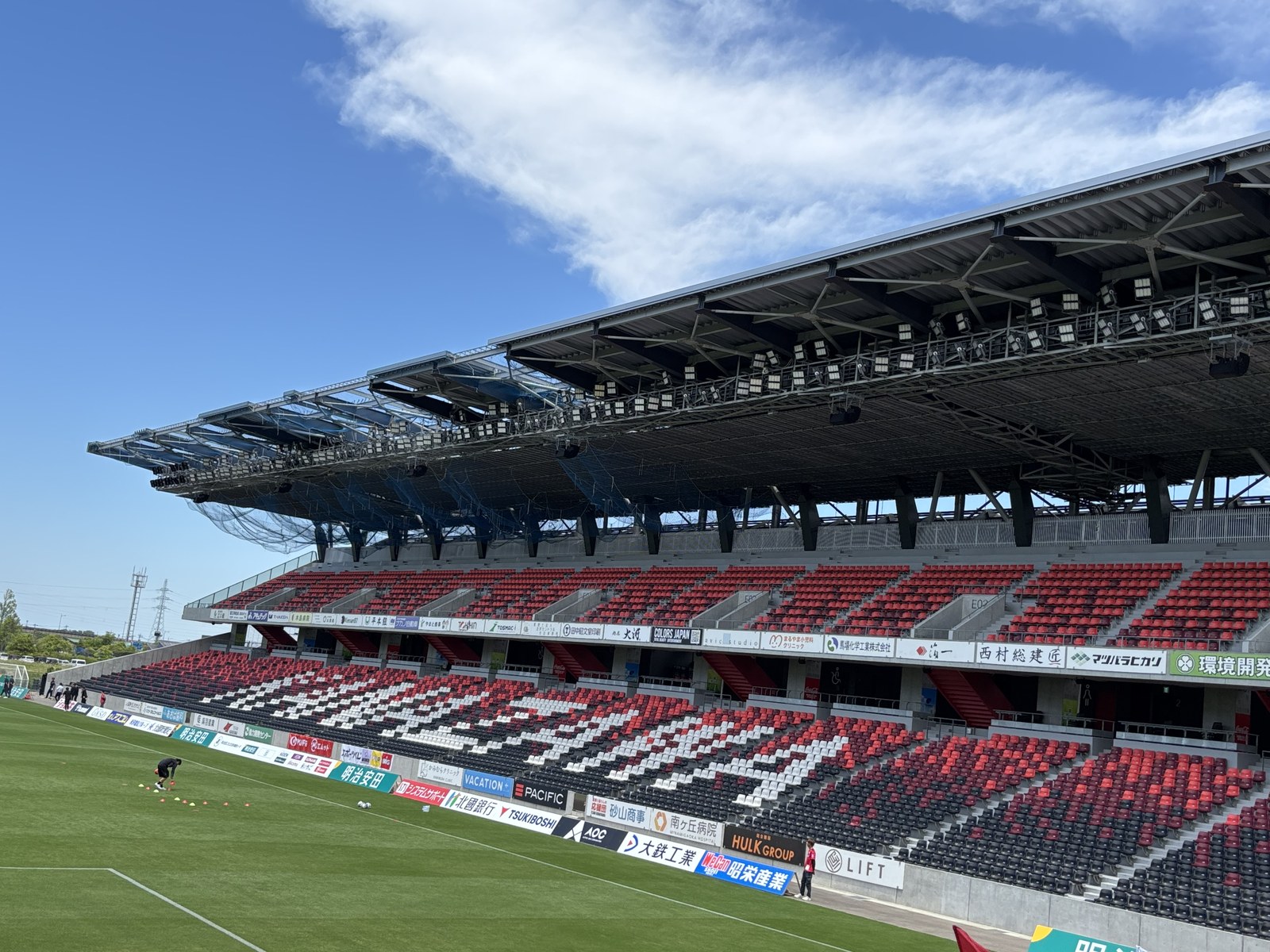 試合前の金沢ゴーゴーカレースタジアム 青空とメインスタンドの赤黒の座席