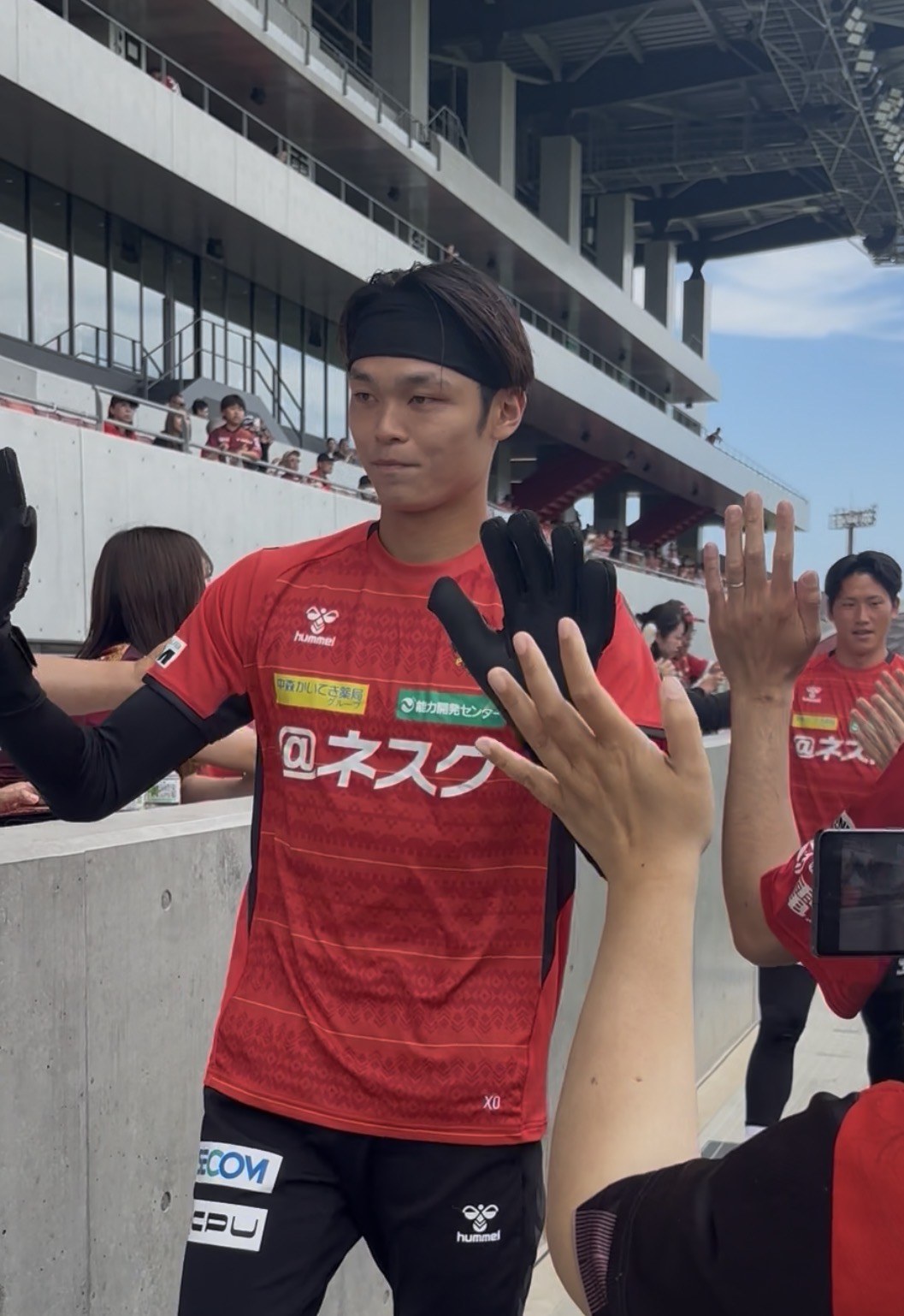 W-UP前ハイタッチで選手と手を合わせるツエーゲン金沢の選手