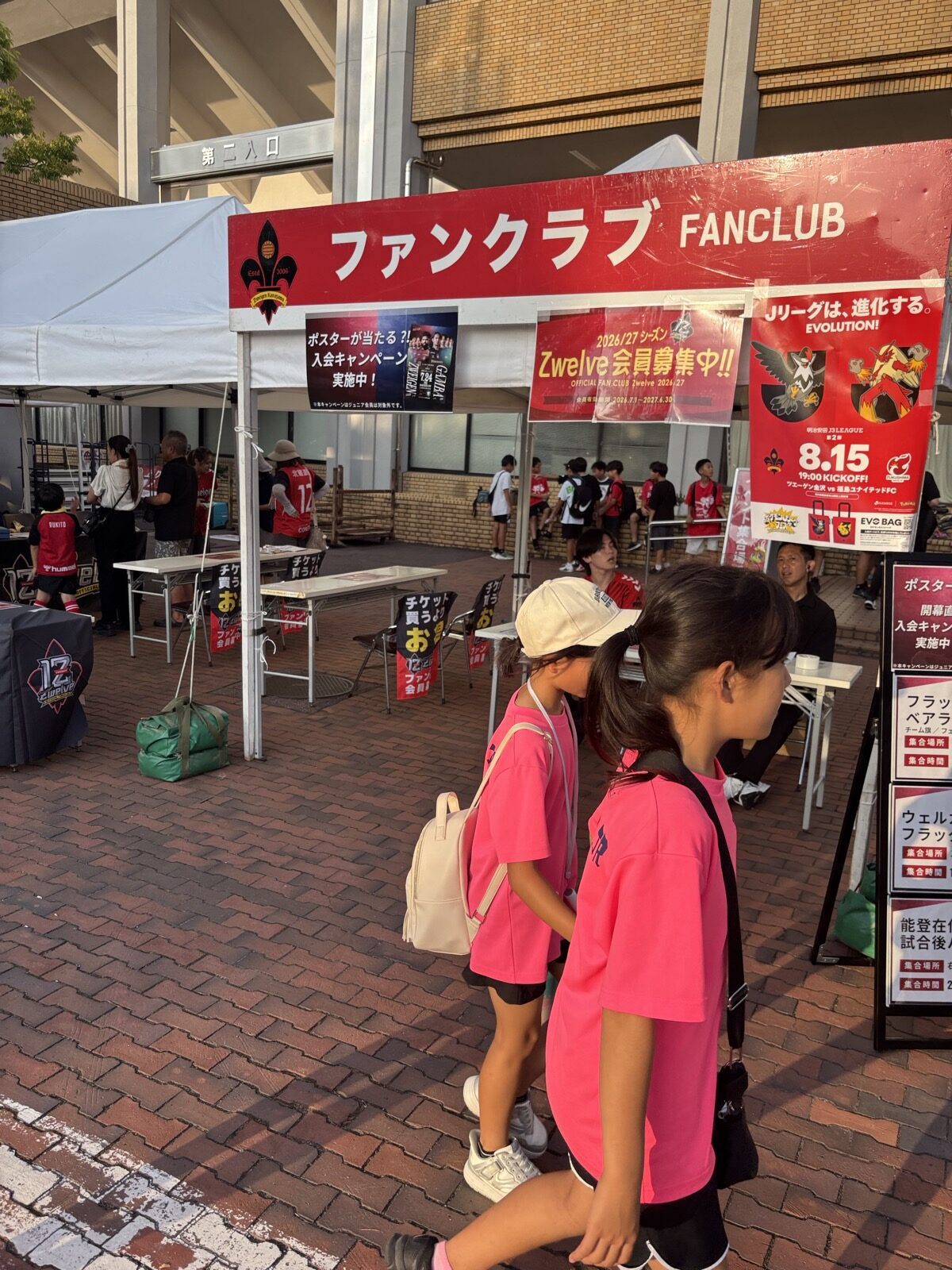 ファンクラブブースの前を歩くツエーゲン金沢のスタッフと子ども
