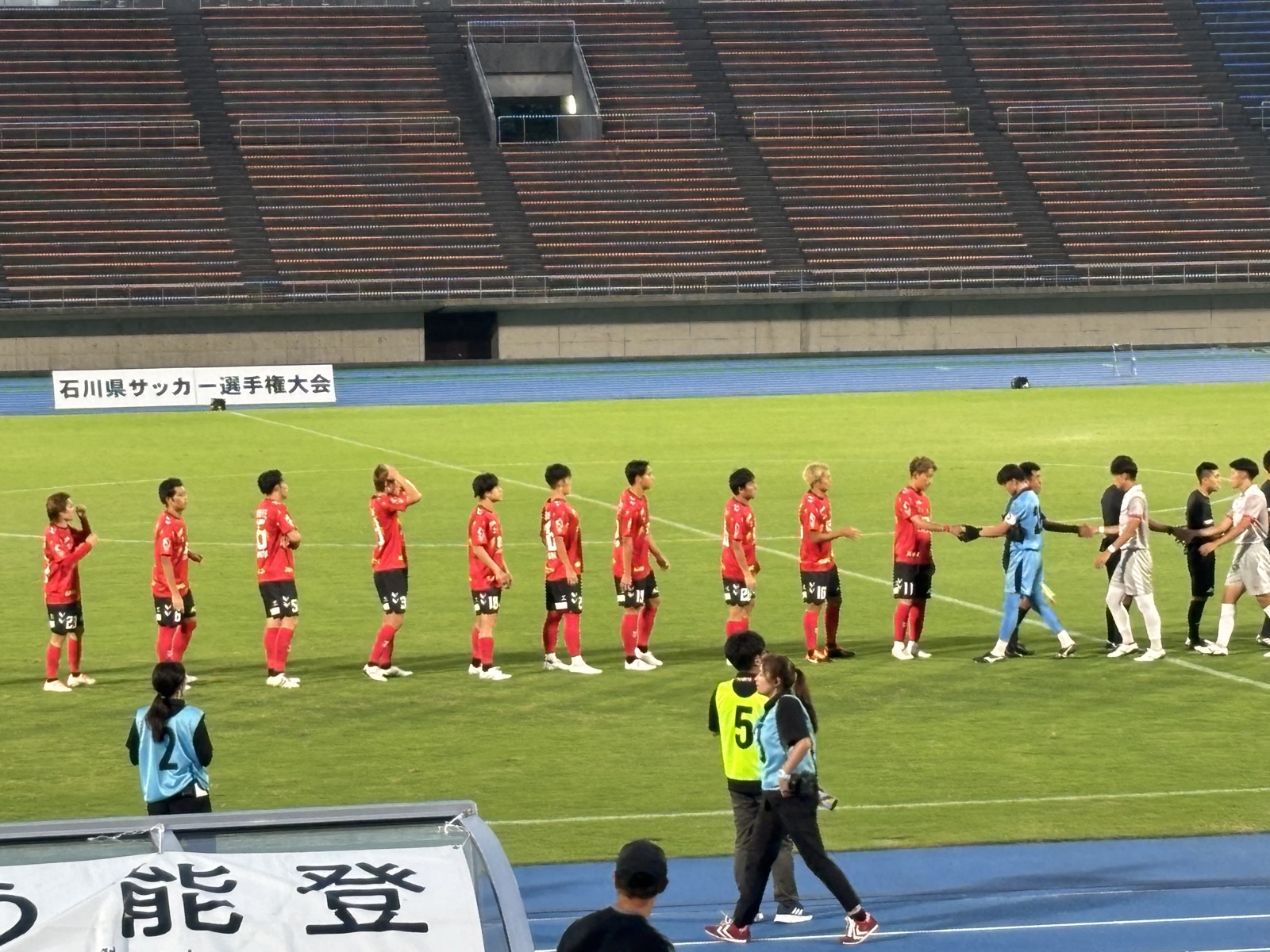 ピッチに整列するツエーゲン金沢の選手たちとがんばろう能登の横断幕